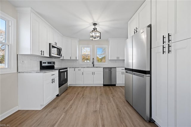 kitchen featuring sink, hanging light fixtures, appliances with stainless steel finishes, decorative backsplash, and white cabinets