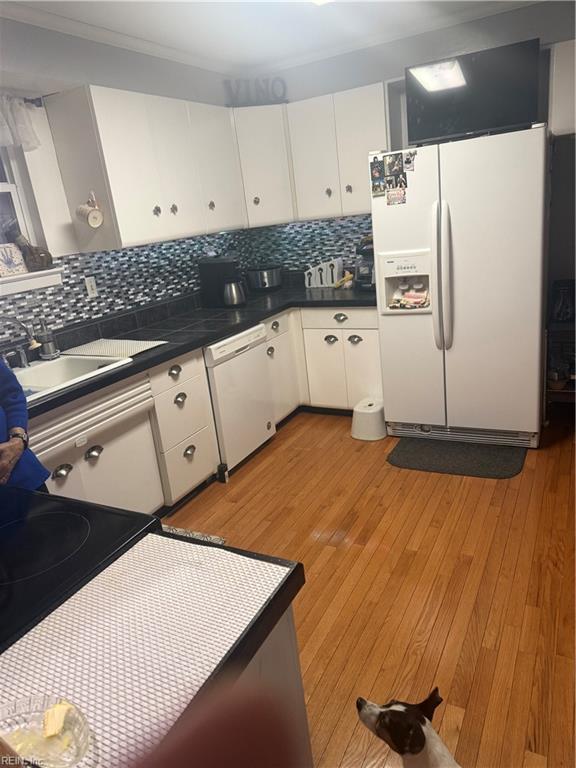 kitchen featuring sink, white appliances, light hardwood / wood-style flooring, white cabinetry, and tasteful backsplash