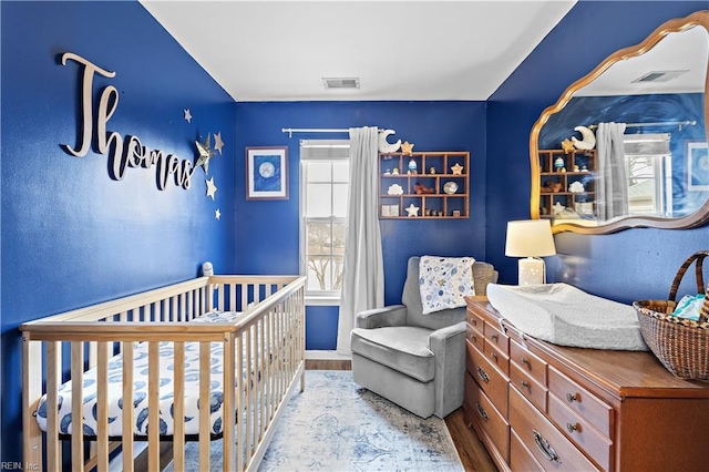 bedroom with a nursery area and light hardwood / wood-style floors