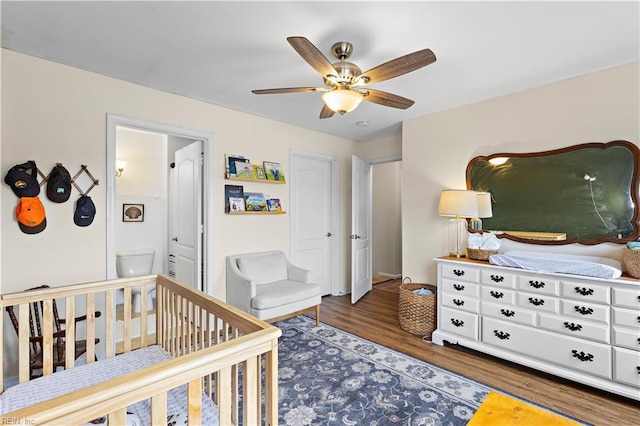 bedroom with a crib, dark hardwood / wood-style floors, and ceiling fan