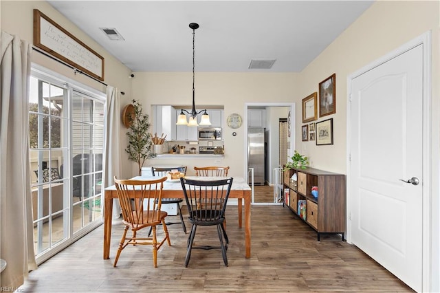 dining room with dark wood-type flooring, plenty of natural light, and an inviting chandelier