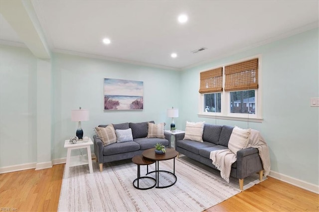 living room with ornamental molding and light hardwood / wood-style flooring