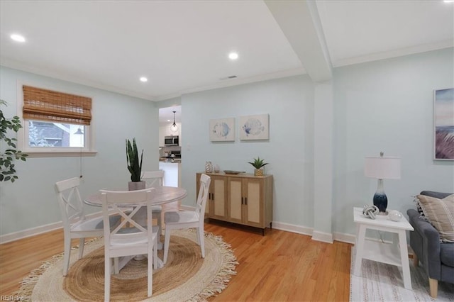 dining area with ornamental molding and light hardwood / wood-style floors