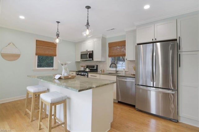 kitchen featuring white cabinetry, sink, a center island, light stone counters, and stainless steel appliances