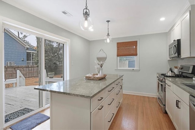 kitchen with appliances with stainless steel finishes, decorative light fixtures, a center island, and white cabinets