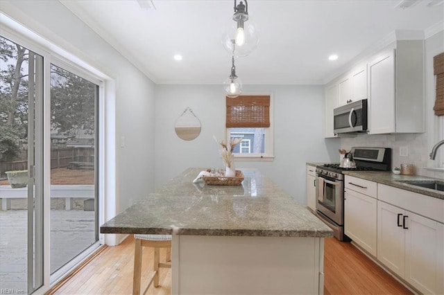 kitchen featuring pendant lighting, sink, appliances with stainless steel finishes, white cabinetry, and light stone countertops