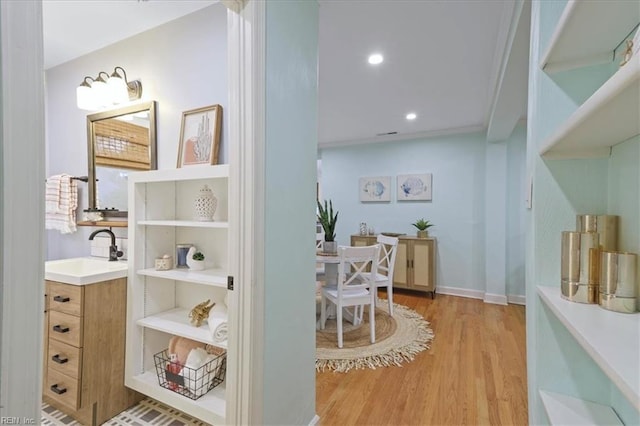 interior space with crown molding, sink, and light hardwood / wood-style floors