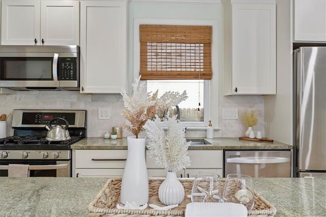 kitchen with decorative backsplash, light stone countertops, white cabinets, and appliances with stainless steel finishes