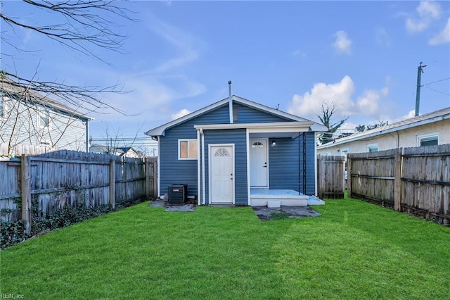 rear view of property with an outdoor structure, a yard, and central AC unit