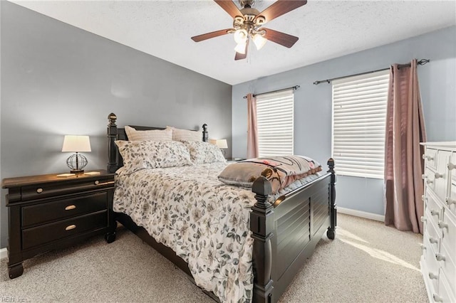 bedroom featuring ceiling fan, light colored carpet, and a textured ceiling