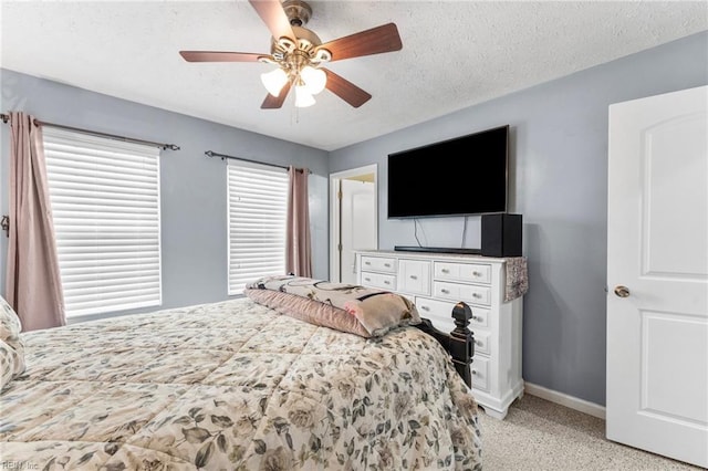 bedroom with ceiling fan, light carpet, and a textured ceiling