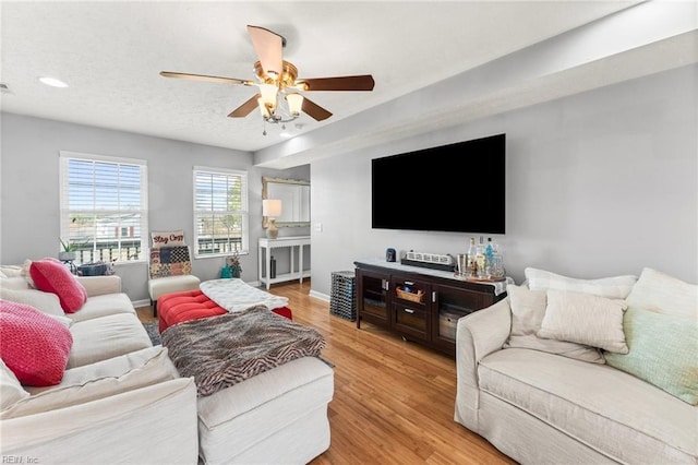 living room featuring ceiling fan, a textured ceiling, and light wood-type flooring