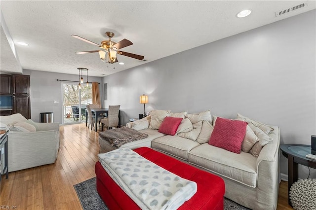 living room with hardwood / wood-style floors, a textured ceiling, and ceiling fan