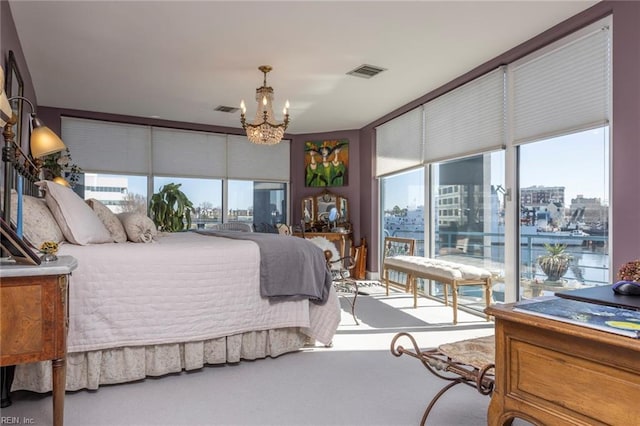 carpeted bedroom featuring multiple windows, visible vents, and a city view