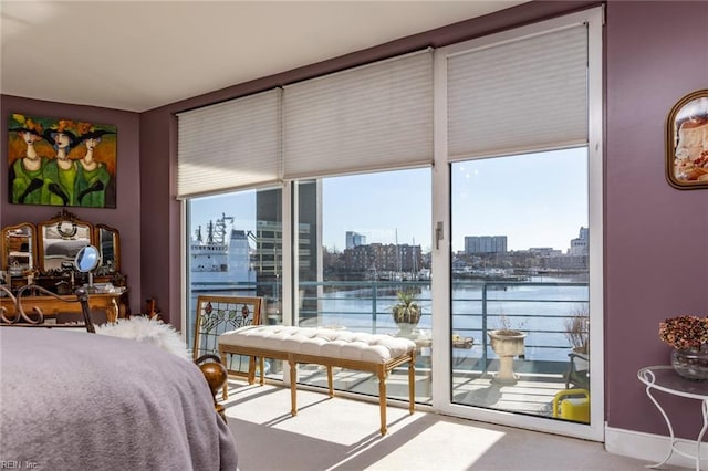 bedroom with access to exterior, a water view, and a city view