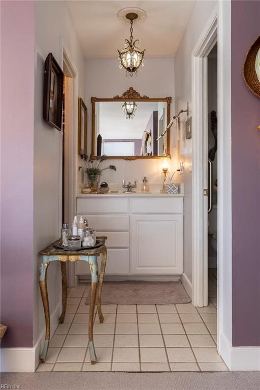 corridor with light tile patterned floors, baseboards, and a notable chandelier