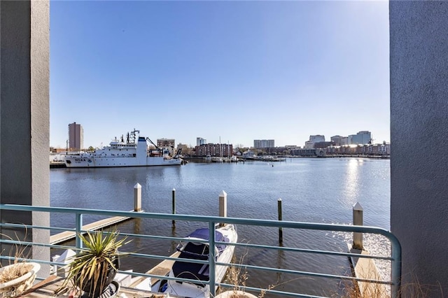 dock area with a water view, a balcony, and a view of city