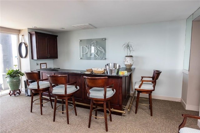 bar with light carpet, visible vents, baseboards, and a dry bar