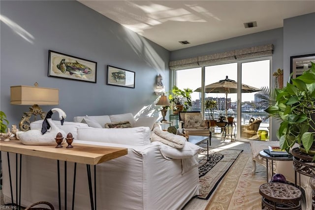 living area featuring light wood finished floors, a water view, and visible vents