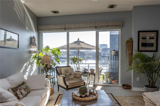 living area featuring visible vents, a water view, and baseboards