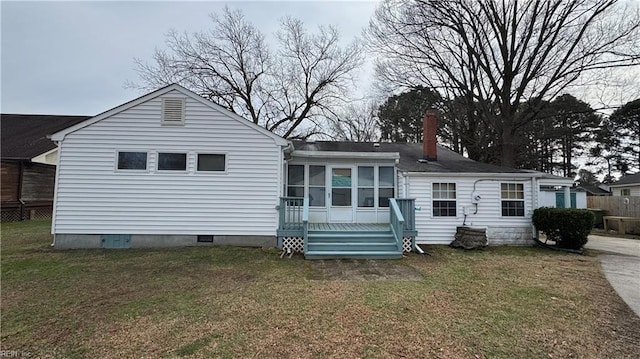 rear view of house with a sunroom and a lawn