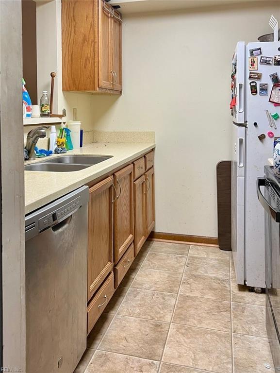 kitchen with white refrigerator, dishwasher, sink, and light tile patterned floors