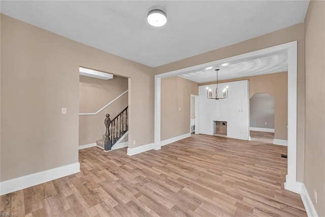 unfurnished living room featuring an inviting chandelier and light hardwood / wood-style flooring