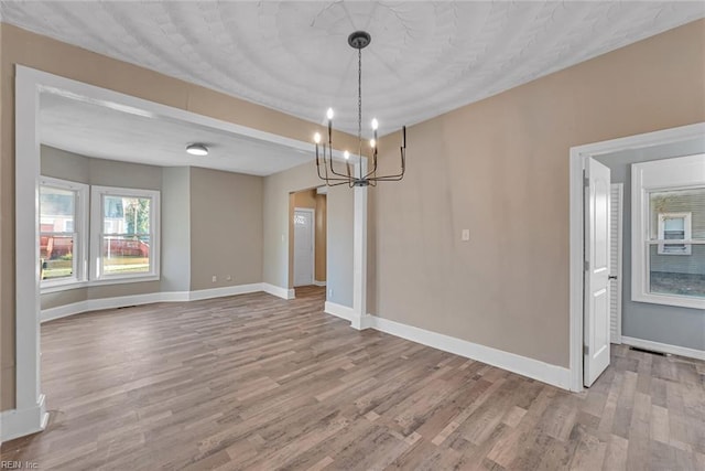 unfurnished dining area featuring hardwood / wood-style flooring and a chandelier