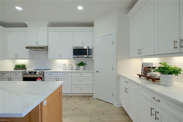 kitchen featuring light stone counters, appliances with stainless steel finishes, backsplash, and white cabinets