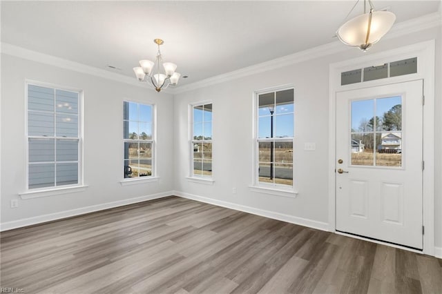 entryway featuring an inviting chandelier, hardwood / wood-style flooring, a wealth of natural light, and ornamental molding