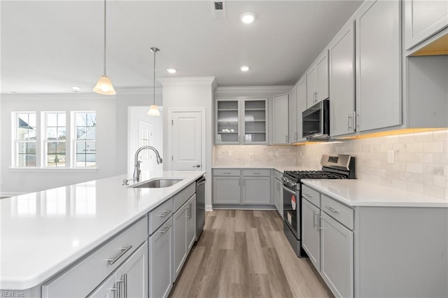 kitchen with decorative light fixtures, tasteful backsplash, sink, gray cabinetry, and stainless steel appliances