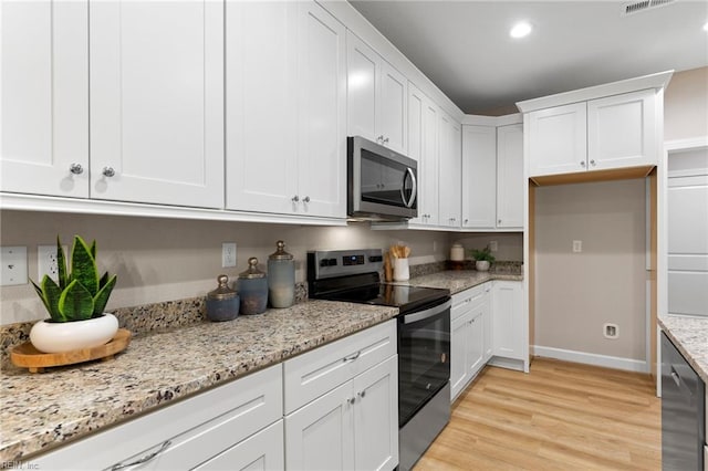 kitchen featuring light stone countertops, white cabinetry, appliances with stainless steel finishes, and light wood-type flooring