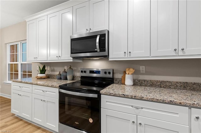 kitchen with light stone countertops, stainless steel appliances, light hardwood / wood-style floors, and white cabinets