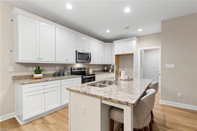 kitchen featuring light stone counters, white cabinetry, a kitchen island with sink, and electric range oven