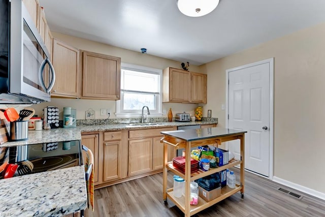 kitchen with stainless steel appliances, sink, light hardwood / wood-style flooring, and light brown cabinets