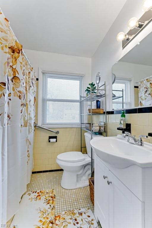 bathroom with tile patterned floors, vanity, tile walls, and a wealth of natural light