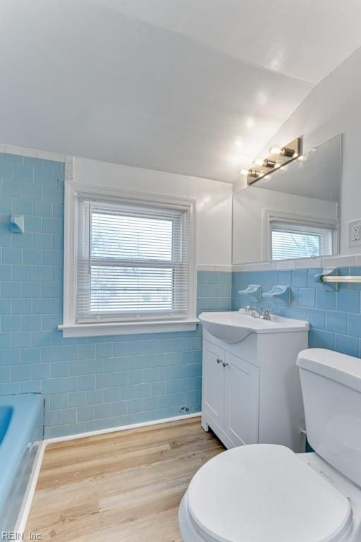 bathroom with lofted ceiling, tile walls, vanity, wood-type flooring, and toilet