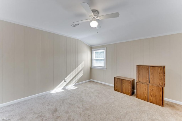 carpeted spare room featuring crown molding, ceiling fan, and lofted ceiling