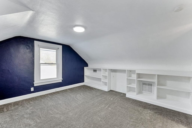 additional living space with vaulted ceiling, carpet floors, a textured ceiling, and built in shelves