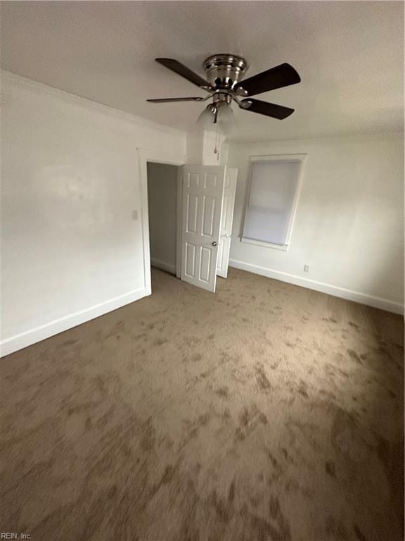 unfurnished room featuring ceiling fan, ornamental molding, and dark colored carpet