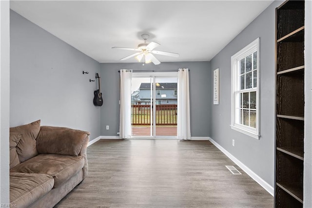 living room featuring wood-type flooring, a healthy amount of sunlight, and ceiling fan