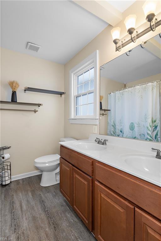 bathroom with hardwood / wood-style flooring, vanity, toilet, and a notable chandelier