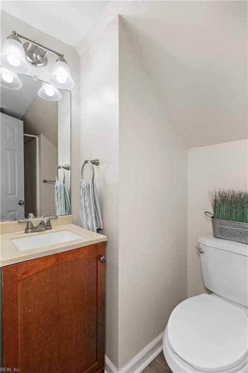 bathroom with vanity, lofted ceiling, and toilet