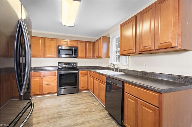 kitchen with appliances with stainless steel finishes, light hardwood / wood-style floors, and sink