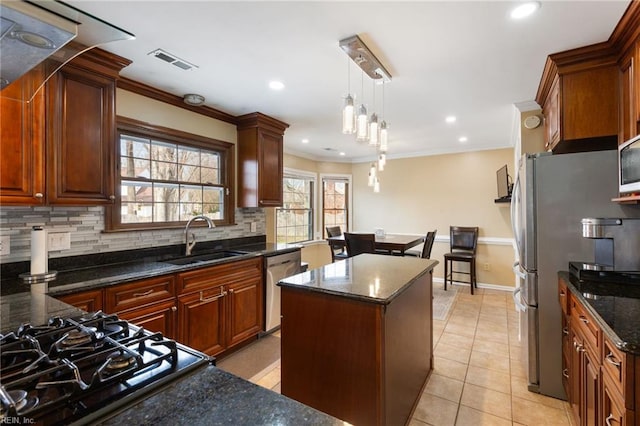 kitchen featuring sink, tasteful backsplash, hanging light fixtures, appliances with stainless steel finishes, and a kitchen island