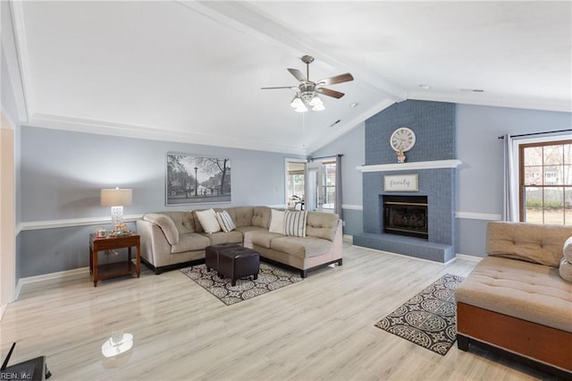 living room with a healthy amount of sunlight, a fireplace, light wood-type flooring, and vaulted ceiling with beams