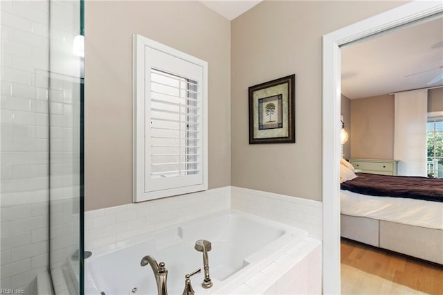 bathroom featuring wood-type flooring and a relaxing tiled tub