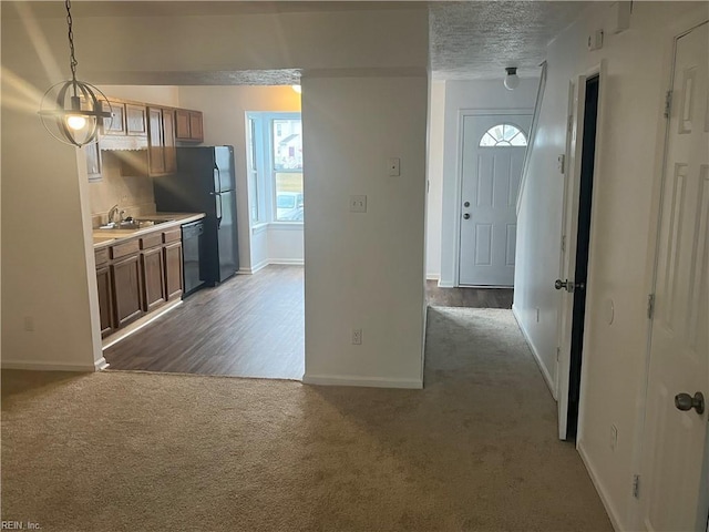 kitchen featuring sink, hanging light fixtures, dark carpet, black appliances, and a textured ceiling