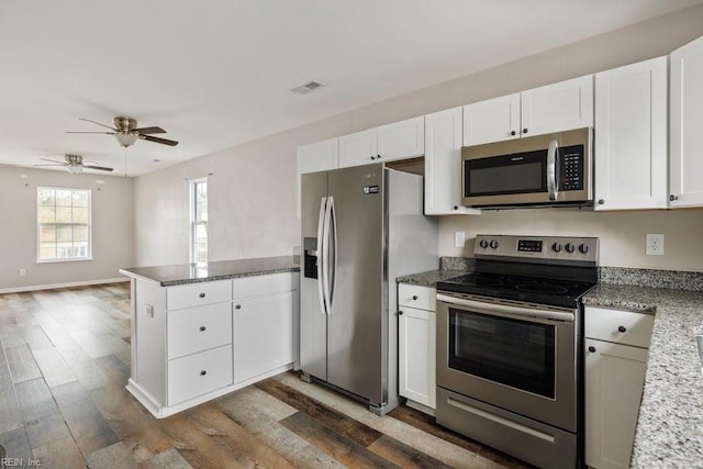 kitchen with white cabinetry, appliances with stainless steel finishes, dark hardwood / wood-style floors, and kitchen peninsula