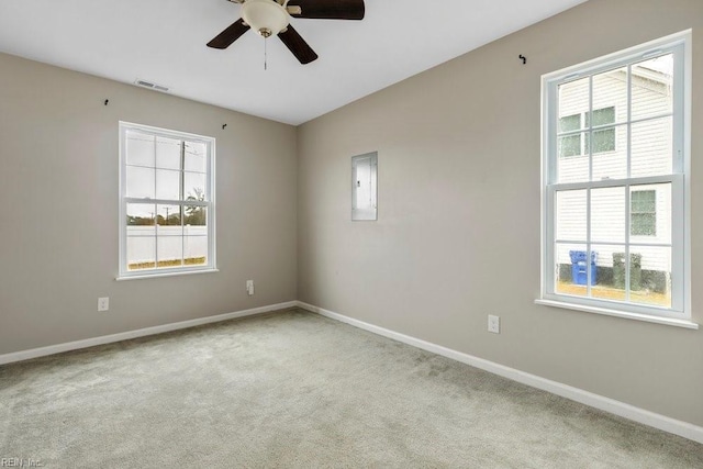 carpeted spare room with a healthy amount of sunlight, electric panel, and ceiling fan